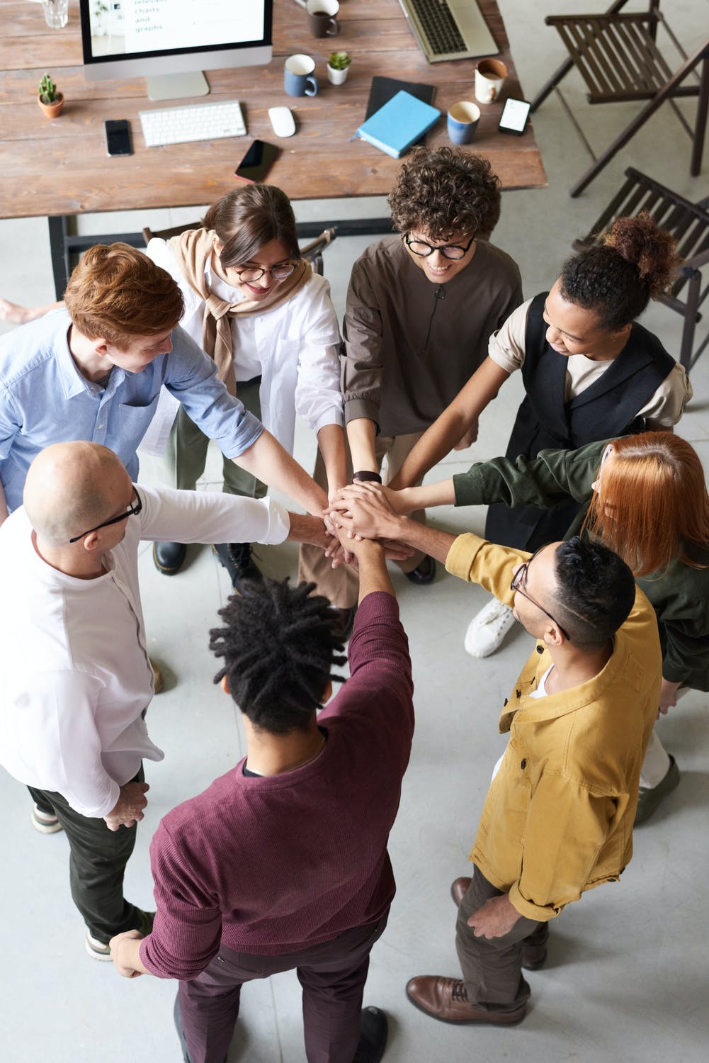 Photographie illustrant Les 5 piliers de l’Employee Value Proposition (EVP). On y voit 9 personnes avec leurs mains au milieu en signe de solidarité et de travail d'équipe. 